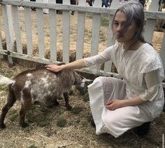 a woman kneeling down petting a small goat