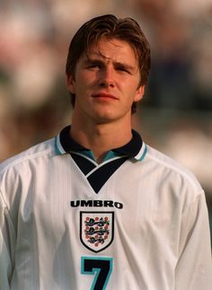 a young man standing in front of a crowd wearing a white shirt and blue tie