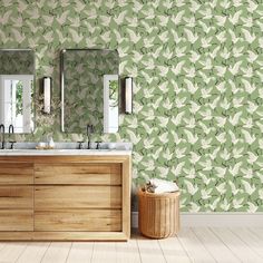 a bathroom with green wallpaper and two sinks in front of a wooden cabinet next to a mirror