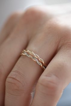 a woman's hand with a gold wedding band and diamond ring on her finger