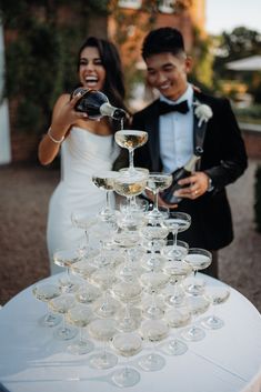 a bride and groom standing next to a table filled with wine glasses