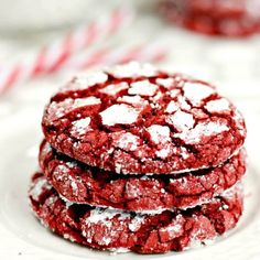 three red velvet cookies on a white plate with candy canes in the back ground