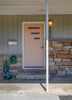 a pink door and some plants on the side of a house in front of a light pole