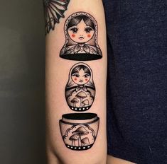 a woman's arm with three little dolls in glass jars on her left arm