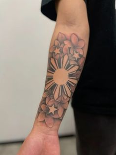 a person with a tattoo on their arm holding up a small piece of art work