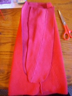 a pair of scissors sitting on top of a table next to a pink piece of cloth