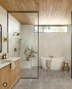 a bathroom with a tub, sink and mirror in it's center wall that has wood paneling on the ceiling