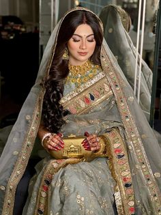 a woman in a gray and gold bridal gown sitting down with her hands clasped