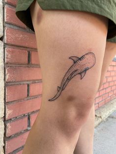 a woman's legs with a tattoo of a dolphin on the lower half of her leg