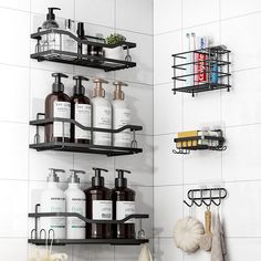 two black shelves with bottles and soaps on them in a white tiled bathroom area