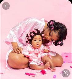 a woman is holding a baby in her lap while she sits on the floor with confetti all around her