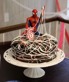 a spiderman cake with white icing and sprinkles sitting on a table