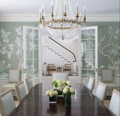 a dining room table with white chairs and flowers in vases on the centerpiece