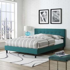 a bedroom with white brick walls and blue bedding in the center, along with two framed pictures on the wall