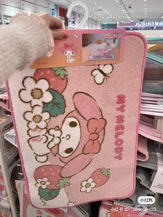 someone is holding up a pink towel with flowers and dog on it in a store