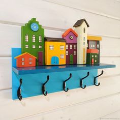 there is a shelf that has some colorful houses on it and hooks attached to the wall