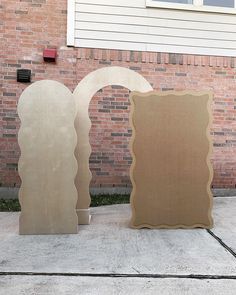 three sculptures are sitting on the sidewalk in front of a brick building with a window