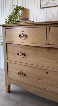 a wooden dresser with three drawers and a potted plant on top of the drawer