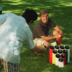 three people are sitting on the grass with wine bottles