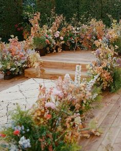 a wooden deck surrounded by lots of flowers