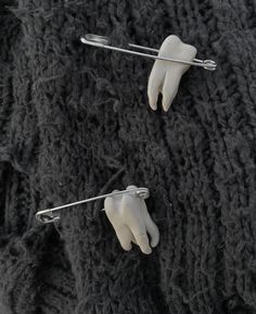 two fake hands are attached to pins on a black knit sweater, one is wearing a white glove and the other has a pair of scissors in it's left hand