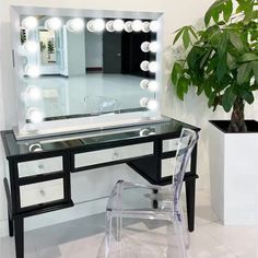 a vanity with lights and a chair in front of it next to a potted plant