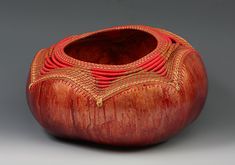 a wooden vase with red and gold designs on the inside, sitting on a gray surface