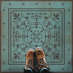 a pair of shoes sitting on top of a floor next to a tile design wall