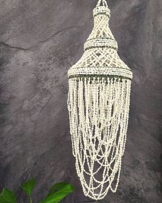 a white beaded chandelier hanging from the ceiling next to a potted plant