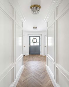 an empty hallway with white walls and wood flooring on either side of the door