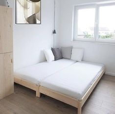 a bed sitting next to a window in a bedroom on top of a hard wood floor