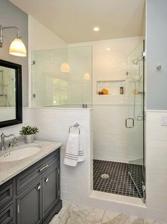 a bathroom with a walk in shower next to a white sink and black cabinetry