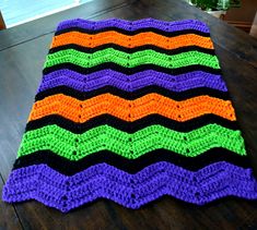 a multicolored crocheted blanket sitting on top of a wooden table