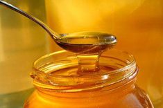 a spoon full of honey sitting on top of a jar