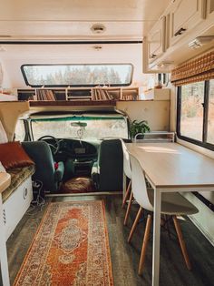 the interior of a camper with a table, chairs and rug on the floor