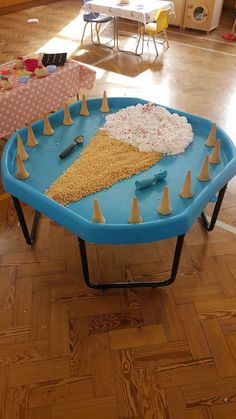 a blue table with cones and cake on it in the middle of a living room