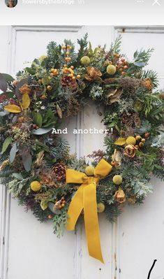 a wreath with pine cones, berries and oranges hanging on a white door that says and another