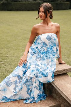 a woman in a blue and white dress sitting on steps