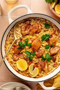 a large pot filled with chicken and rice on top of a table next to lemons