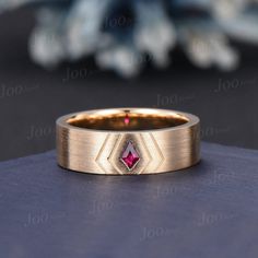 a gold ring with a pink diamond in the center on top of a blue surface