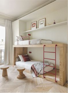 two bunk beds in a room with white walls and wood flooring on the side