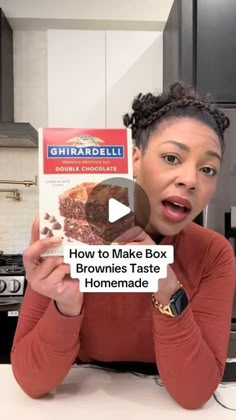 a woman holding up a box of brownies in her kitchen with the words how to make box brownies taste homemade