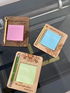 three wooden coasters with sticky notes and pens on them sitting on top of a glass table