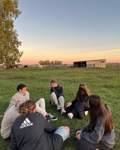 group of people sitting on the grass in a circle