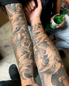 two people with tattoos on their arms holding bottles