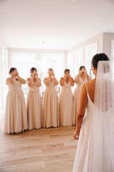 a bride and her bridal party are looking at each other in front of the mirror