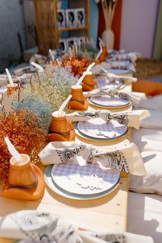 there are many plates on the table with flowers in vases next to each other