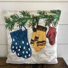 two mittens hanging from a christmas tree on a pillow