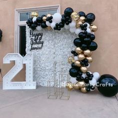 black and gold balloons are on display in front of a happy 21st birthday balloon arch