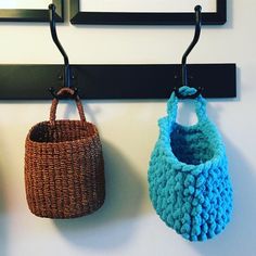 two crocheted purses hanging from hooks on a wall